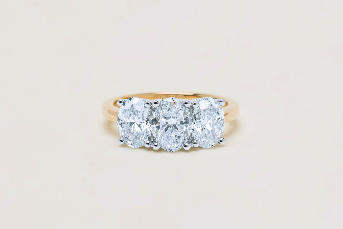 Three stone oval cut diamond ring on neutral background