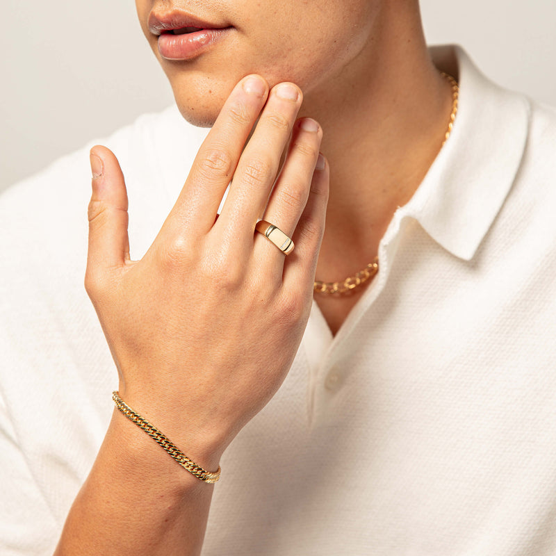 Model wearing gold and diamond signet ring, bracelet and chain