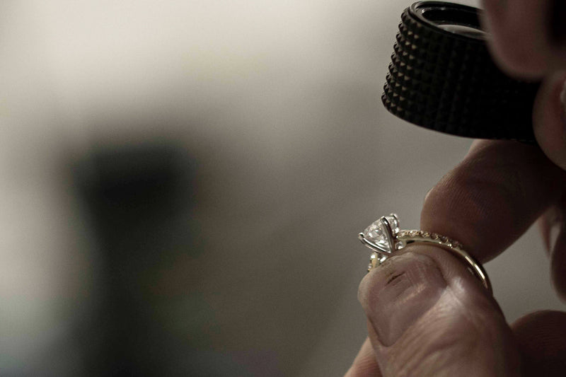 Jeweller inspecting diamond ring through a loupe