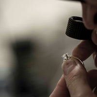Jeweller looking at diamond ring through loupe
