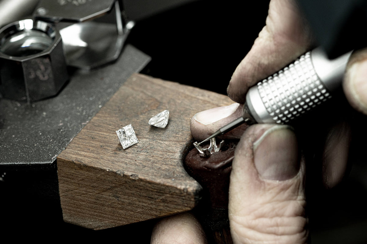 Jeweller at a work bench preparing a ring setting for a diamond