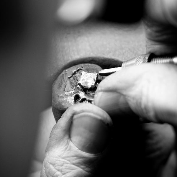 Jeweller adjusting prongs on diamond ring at jeweller's bench