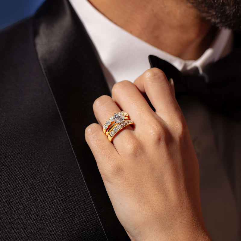 Model wearing diamond engagement ring resting her hand on partner's tux collar