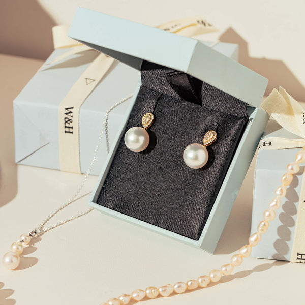 Flat lay with Pearl Earrings in gift box and pearl necklaces draped over Walker & Hall gift boxes