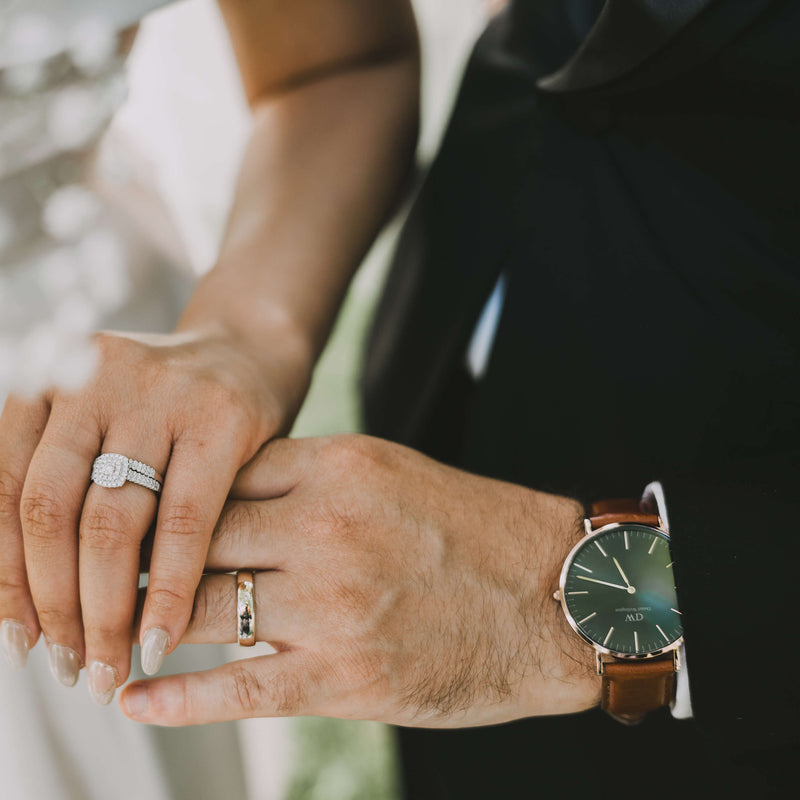 Bride and groom holding hands wearing wedding rings and groom wearing a Daniel Wellington watch