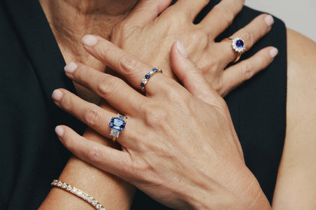 Close-up of hands wearing sapphire and diamond rings