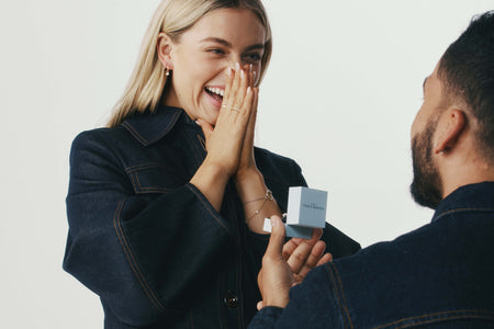 Man proposing to his partner with a Walker & Hall ring box