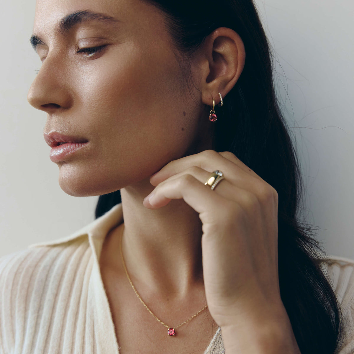 Close up of woman wearing Ocatvia coloured gemstone necklace and earrings and diamond earrings and rings