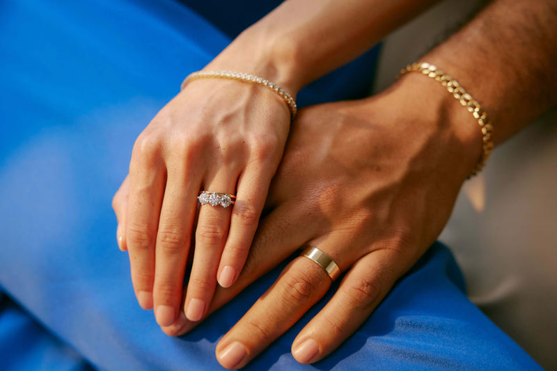 Couple holding hands wearing wedding and engagement rings