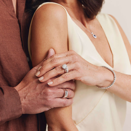 Couple holding hands, female wearing diamond engagement and wedding rings